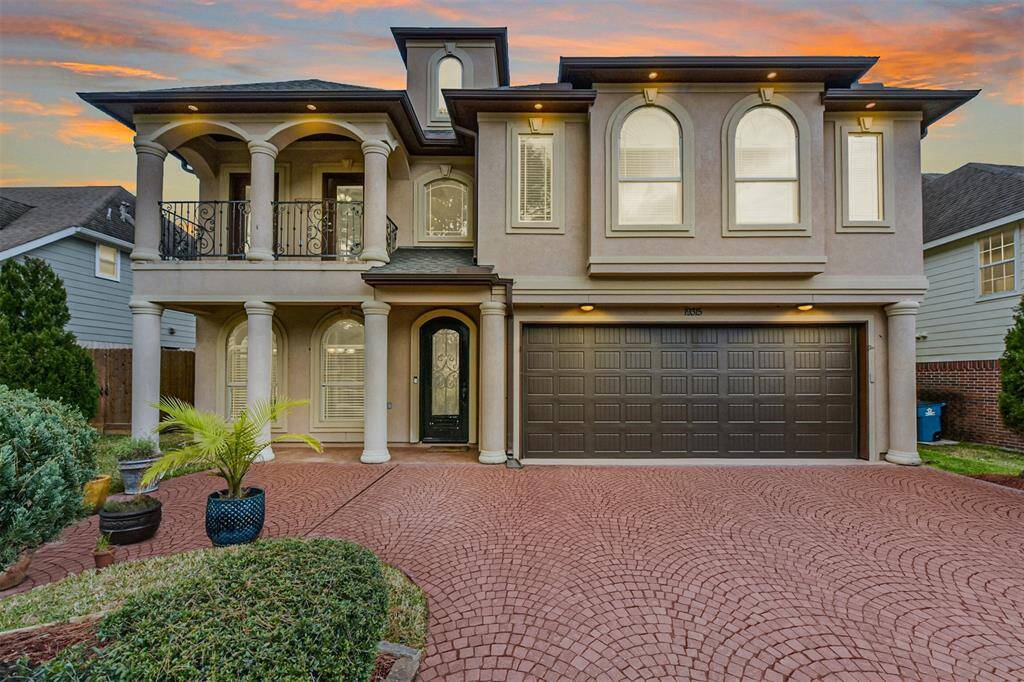 Custom stucco Mediterranean with concrete paver driveway.