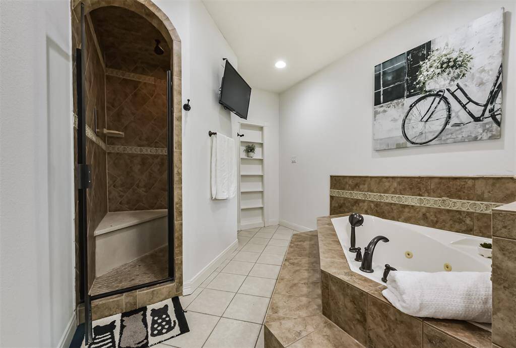 Oversized shower with 3 shower heads and bench seat.