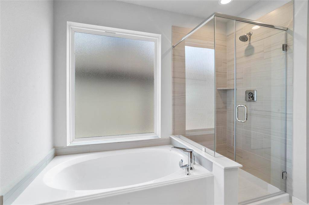 This primary bathroom is definitely move-in ready! Featuring dark framed walk-in shower with tile surround, separate garden tub for soaking after a long day with custom tile detailing, high ceilings, custom paint, sleek and dark modern finishes!