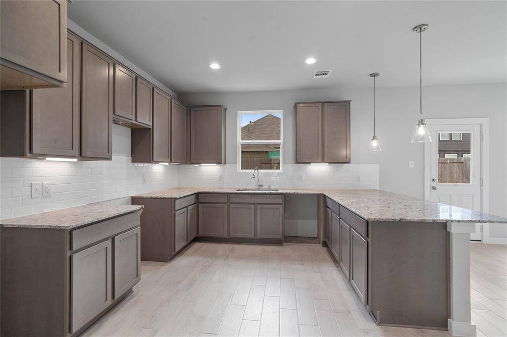 This kitchen is by far any chef’s dream! This spacious kitchen features high ceilings, stained wood cabinets, granite countertops, SS appliances, modern tile backsplash, recessed lighting, pendant lighting, and a walk-in pantry all overlooking your huge family room.