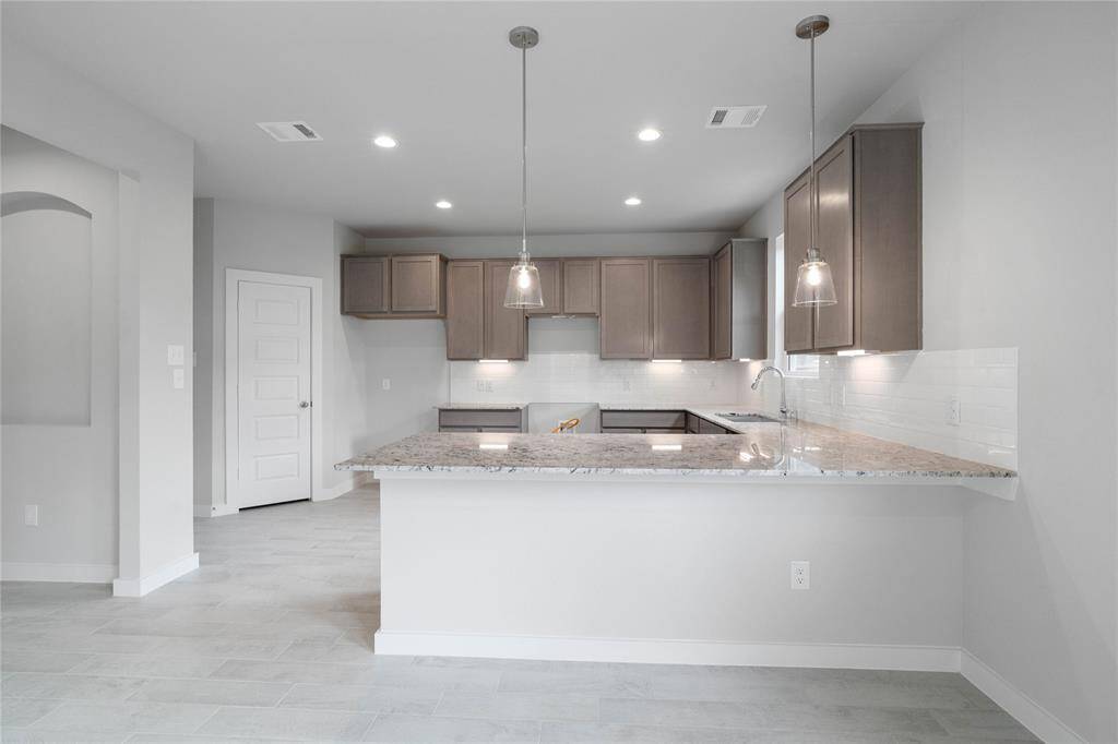 This kitchen is by far any chef’s dream! This spacious kitchen features high ceilings, stained wood cabinets, granite countertops, SS appliances, modern tile backsplash, recessed lighting, pendant lighting, and a walk-in pantry all overlooking your huge family room.