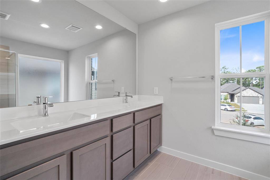This large primary bath is spacious enough to share! With separate vanities, plentiful cabinet and counter space, you are sure to have private area while sharing this bathroom!