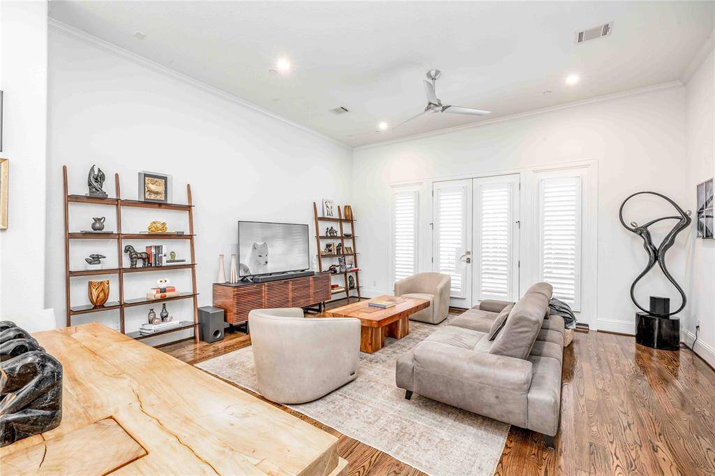 This spacious, modern living room features hardwood floors, ample natural light through large windows with custom 4" plantation shutters.