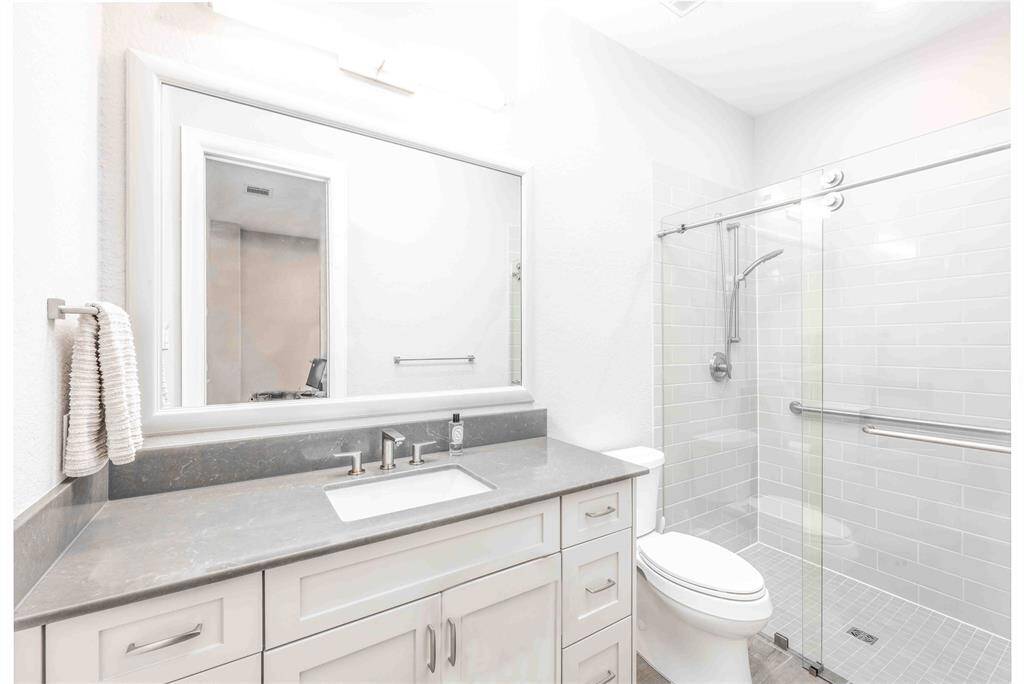 Explore the modern elegance of this first-floor ensuite bathroom, featuring a sleek glass enclosure, updated fixtures, and stylish cabinetry.