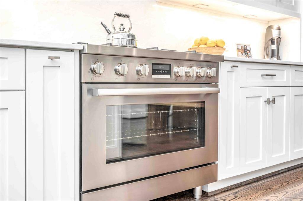This kitchen features a sleek stainless steel BOSCH Range, surrounded by elegant cabinetry. The clean design is complemented by a bright countertop and under-cabinet lighting, creating a contemporary and inviting cooking space.