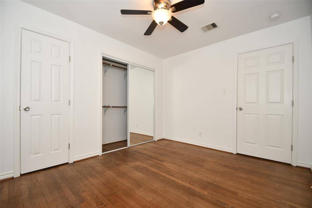 Spacious bedroom with a cozy closet and elegant hardwood floors.