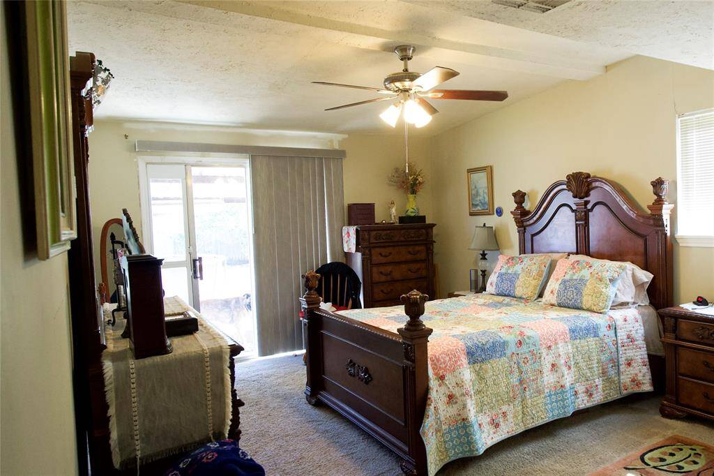 This cozy bedroom features  natural light from a window and sliding glass doors, offering easy access to the outdoors.