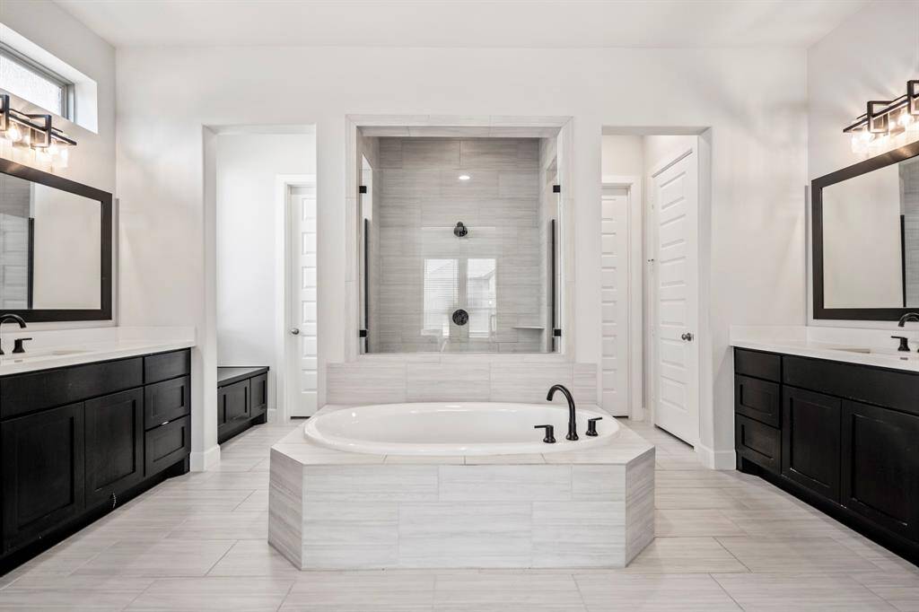 Experience luxury in this expansive primary bathroom, complete with a large garden tub, walk-in shower, sleek quartz countertops, and contemporary tile accents — the perfect oasis for relaxation and rejuvenation.