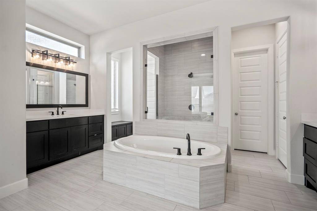 Indulge in the spaciousness of this primary bathroom! It it features two large separate vainty areas with upgraded framed mirrors, modern overhead lighting, quartz countertops, and plenty of storage space.