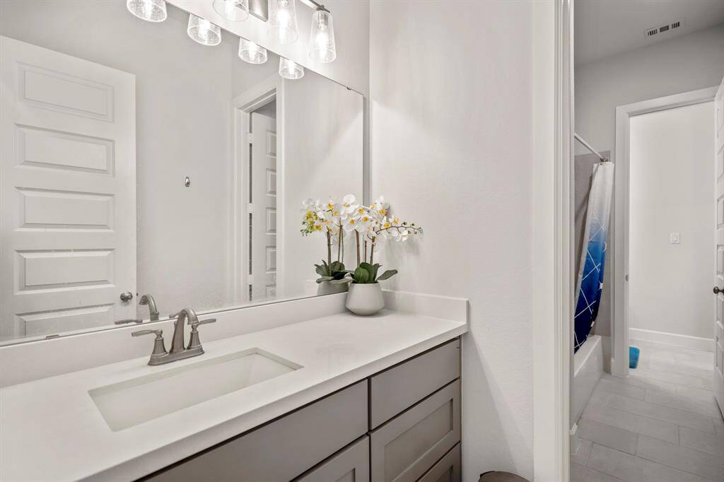 A jack and jill bathroom is the perfect set up for sharing! This private vanity area features quartz countertops, a large mirror, wood painted cabinets, and direct access to the combination tuv and shower.