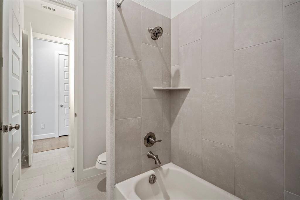 The jack and jill bathroom includes a large combination tub and shower with sleek tile surround. It's the perfect layout making it easy to share and the perfect place to unwind