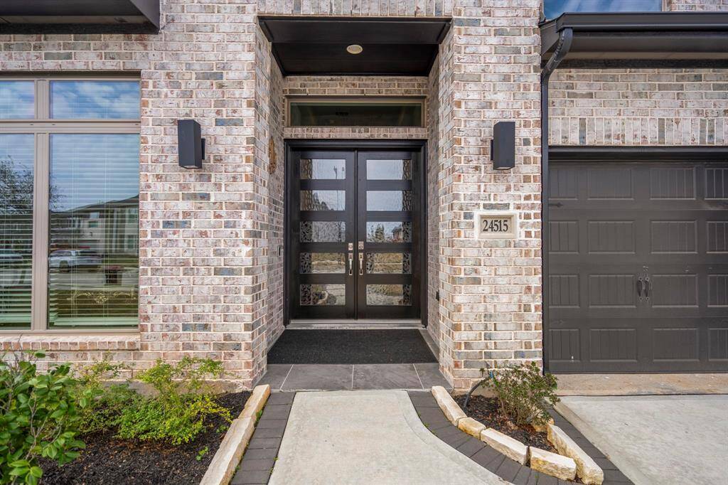 As you approach the home, you're greeted by a stunning first impression—an upgraded tile porch leading to modern mahogany double doors. Framed by sleek black lanterns, the entrance exudes warmth and contemporary elegance, setting the tone for the rest of the home.