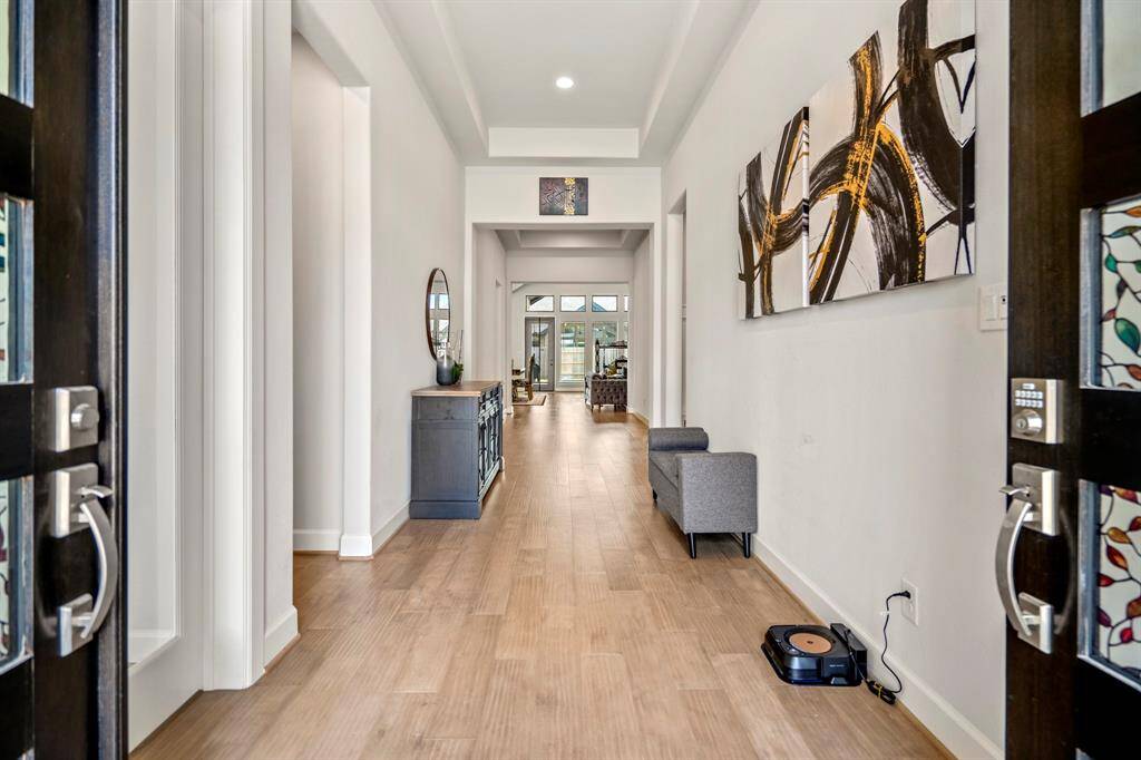 Stepping through the grand double doors, you're welcomed into an elegant entryway with stunning wood-look tile flooring that extends throughout the first floor main areas making it easy and clean to maintain. The high trace ceilings, open design, and natural light create a warm, welcoming atmosphere, setting the perfect tone for the rest of the home.
