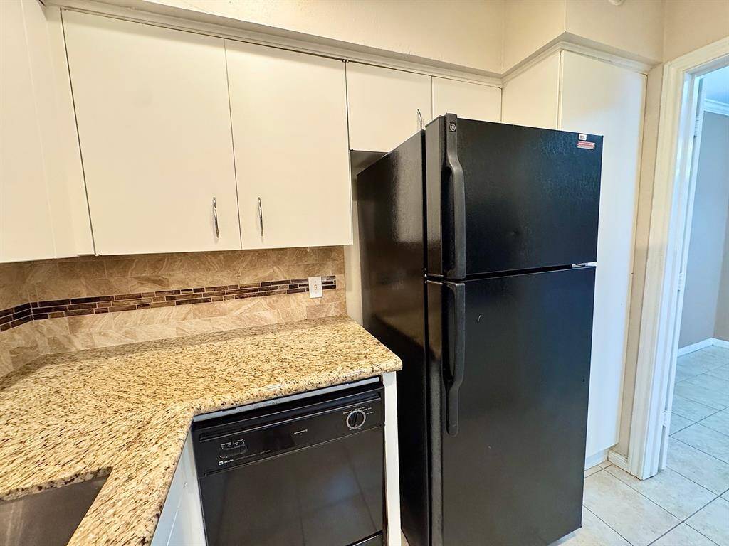 Custom backsplash all around for easy maintenance. The pantry is to the right of the refrigerator.