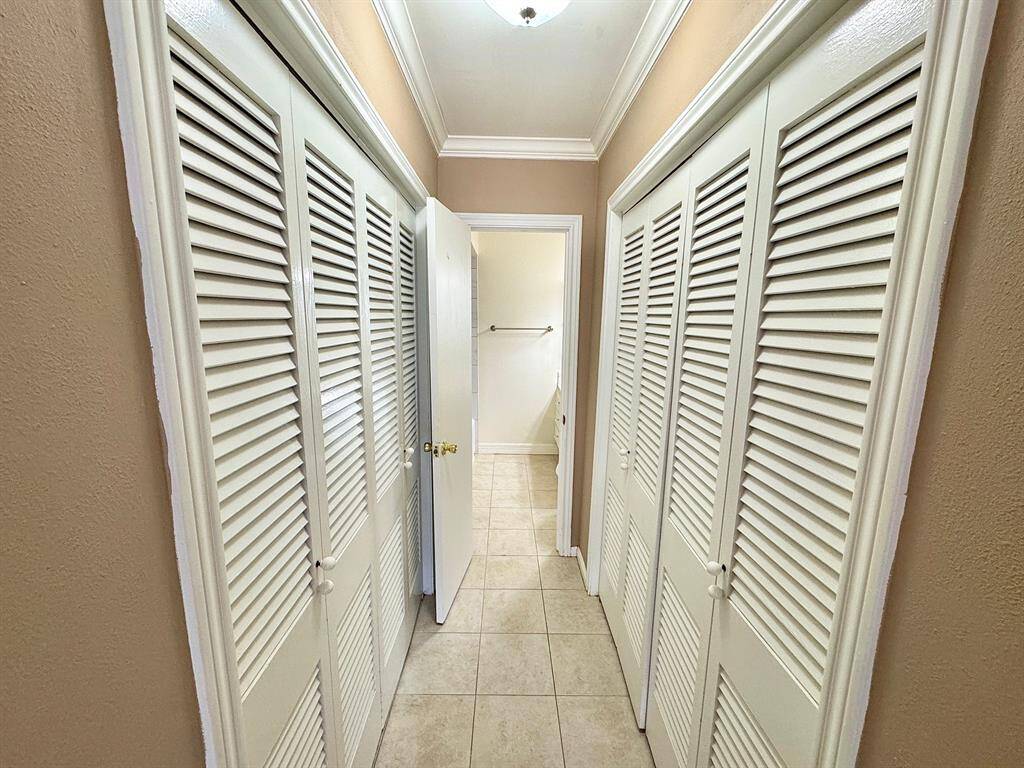 Primary bedroom closets line the hallway to the ensuite bath.