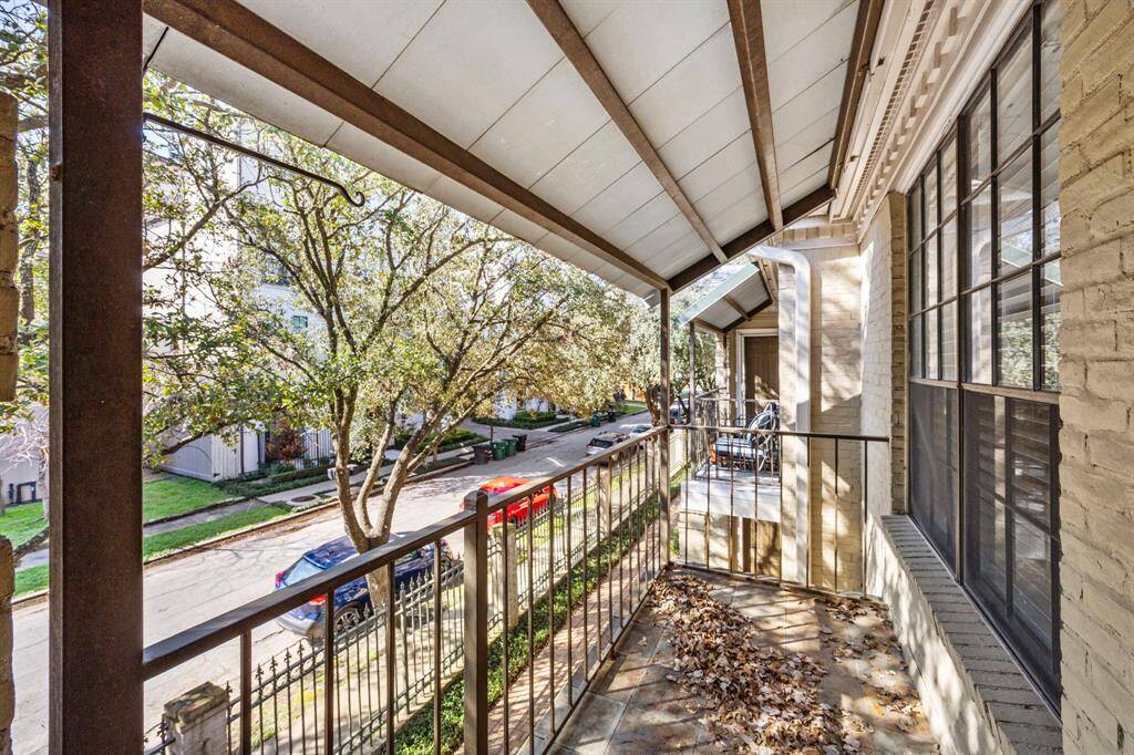 Enjoy fresh air and charming neighborhood views from this covered balcony with wrought iron railing and ample space for seating. *Tile was digitally cleaned and altered.