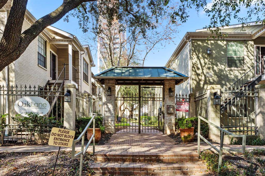 Oak Lane Condominiums, a charming gated community featuring elegant brick architecture, lush landscaping, and secure entry in a prime location.