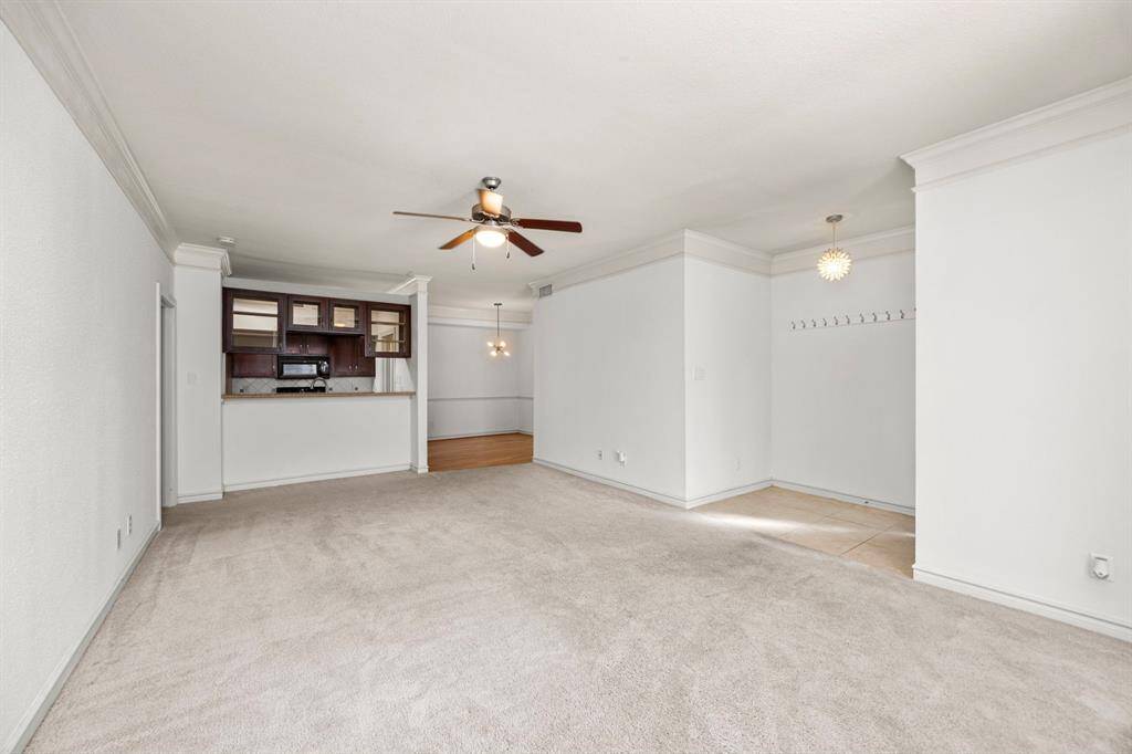 Living area features elegant crown molding, plush carpeting with views to the kitchen and dining room. Newly painted living room, kitchen, dining room, and secondary bedroom.