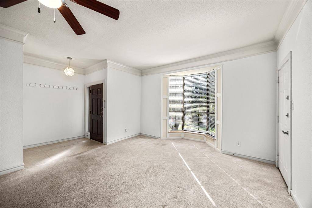 This bright and inviting living space features a charming bay window, elegant crown molding, and a stylish entryway.