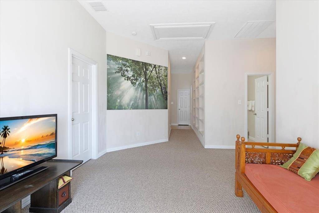 There is a halway lined with floor to ceiling book shelves that leads to a sitting room and the three secondary bedrooms. These rooms are located behind the kitchen and private from the rest of the home.