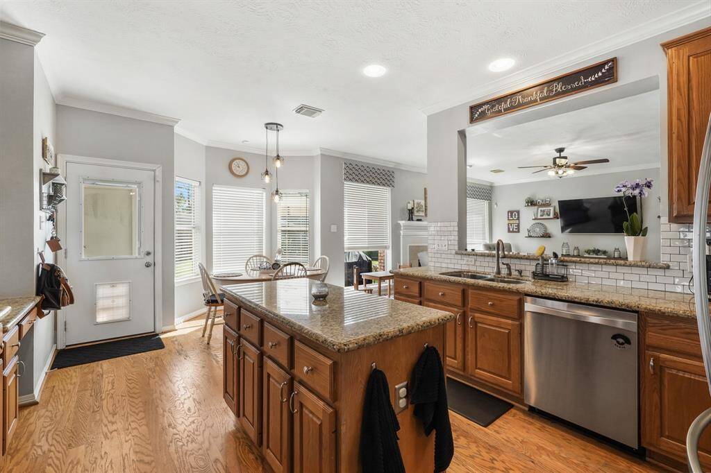 Experience elegance in the kitchen with granite countertops, warm wood cabinets and flooring, and a striking white subway tile backsplash.