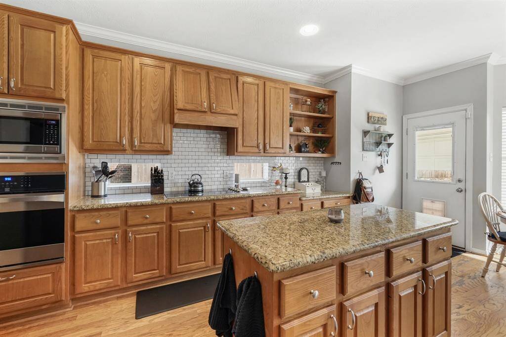 Brighten your kitchen with small windows above the counters and enjoy open shelves for display. A door from the breakfast room conveniently leads to the backyard and garage walkway.