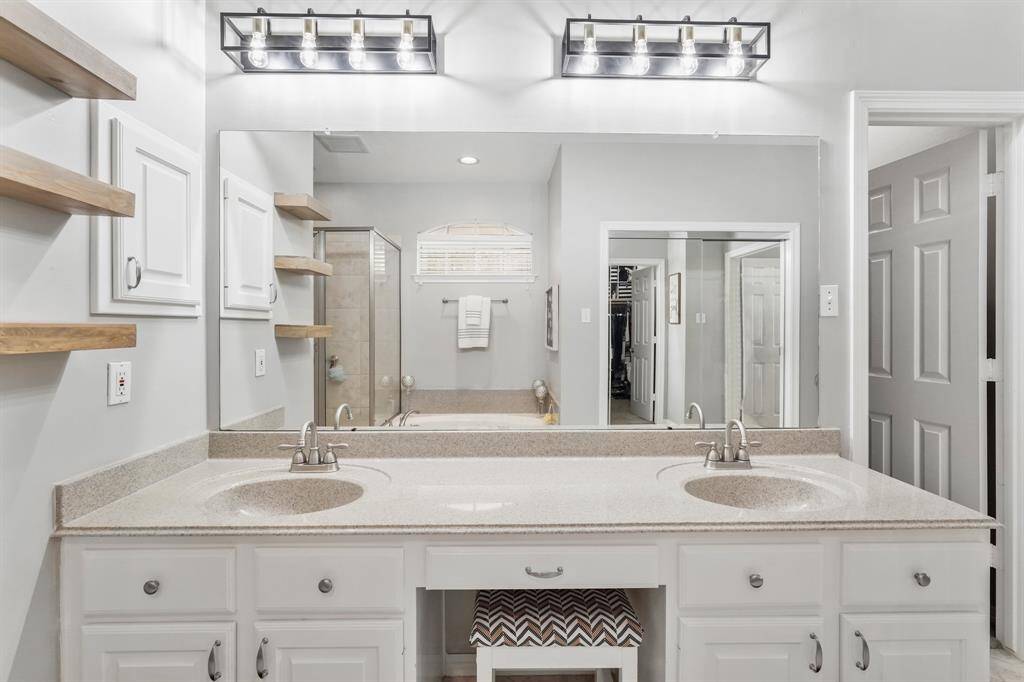 A wonderful dual-sink vanity is perfect for this space. It rests under an oversized mirror with stylish lighting.