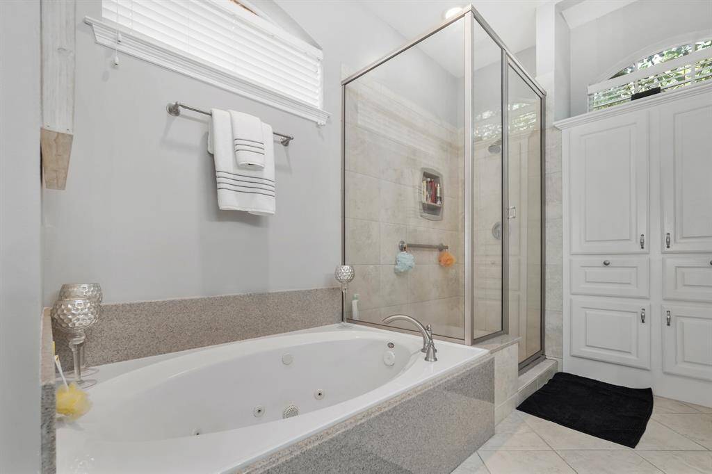 Unwind in a jetted tub at the end of a long day. A high window above it provides natural light without affecting privacy. Notice the built-in linen closet near the shower. There is so much space for storing everything you need.