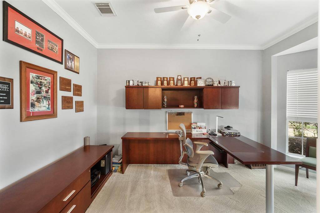 Elegant office with crown molding, French doors, and a bay window offering a serene front yard view.This photo is staged for photo purpose.