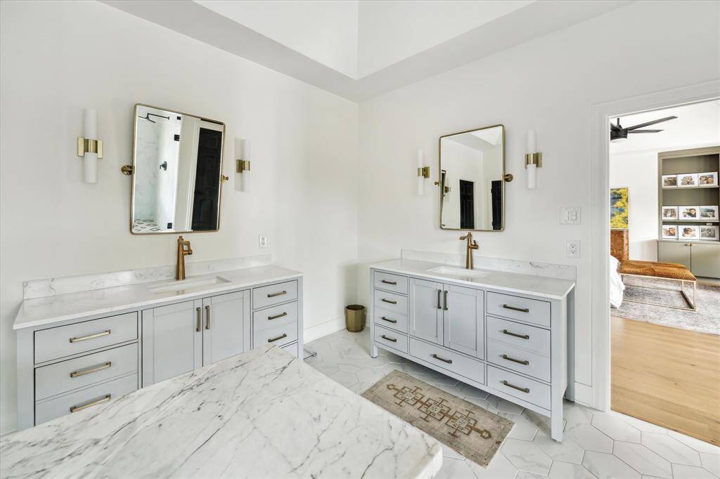 The elegant ensuite bathroom features dual vanities with Moen plumbing fixtures, luxurious quartz countertops, and Aerin sconces, combining timeless style with modern sophistication.