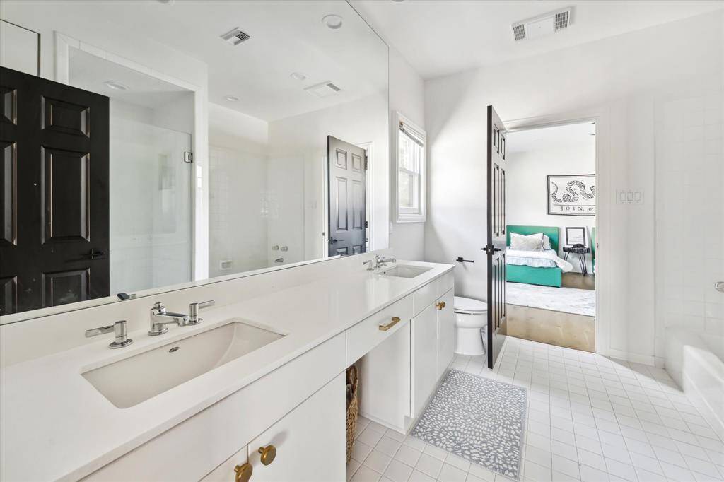 A stylish Jack and Jill bathroom connects two of the secondary bedrooms and features dual sinks, sleek finishes, and ample storage for convenience and functionality.