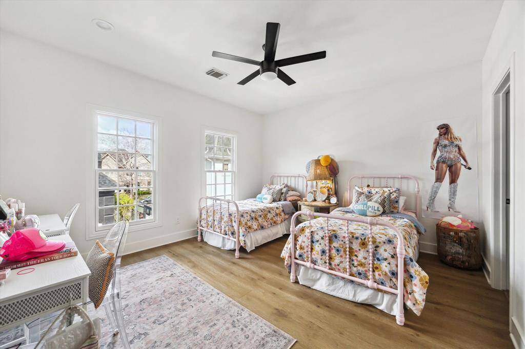 Bright and inviting, this secondary bedroom features large windows, hardwood floors, and a modern ceiling fan, offering both comfort and charm.