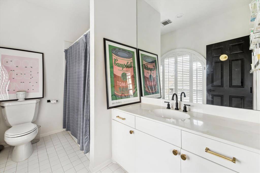 Blending modern and classic elements seamlessly, this stylish ensuite bathroom boasts a sleek vanity with brass hardware, a black matte faucet, and a charming arched window.
