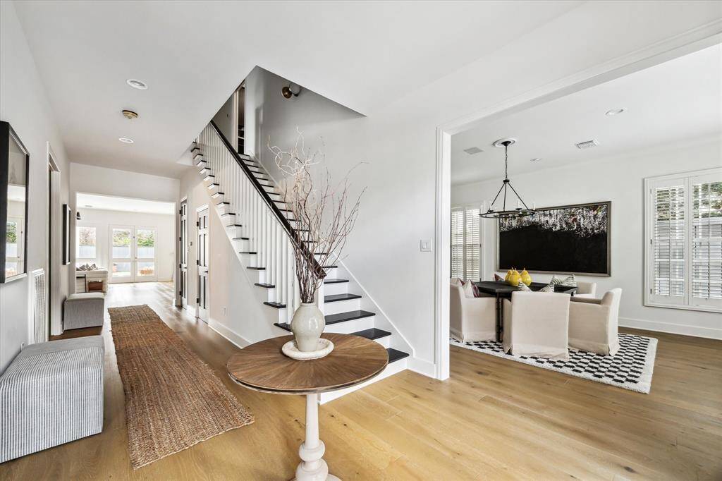 This airy foyer features sleek design elements, with a graceful staircase as its centerpiece and wide openings that lead to the formal living, formal dining, study, and family room.