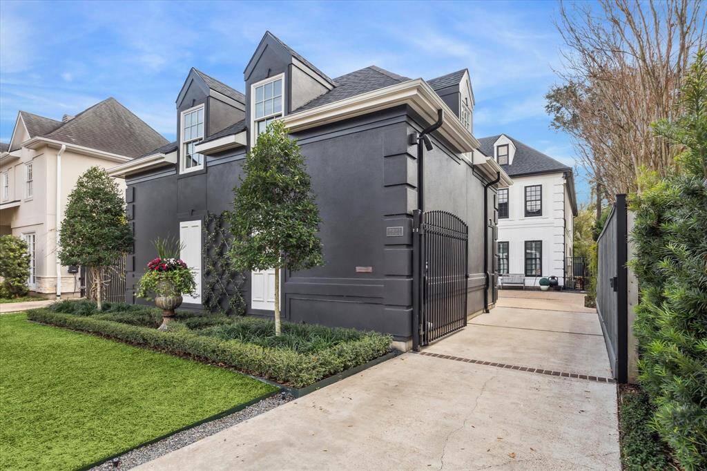 This beautifully remodeled West University home features a gated driveway, manicured landscaping, and a striking black-and-white exterior for exceptional curb appeal.