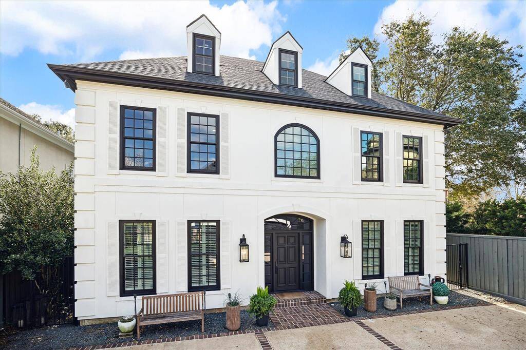 The timeless elegance of this West University residence is on full display. With its bold black-and-white façade, charming dormer windows, and stately architectural details, this home perfectly blends classic sophistication with modern luxury. A beautifully framed entryway, accented by brick and lush landscaping, leaves a lasting impression of warmth and refinement.