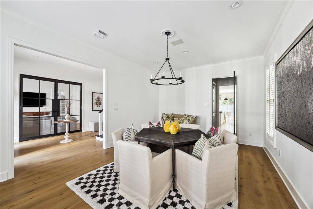 The formal dining room features abundant natural light, sleek plantation shutters, and a modern chandelier. The open design and clean lines create a versatile space perfect for hosting or everyday use.