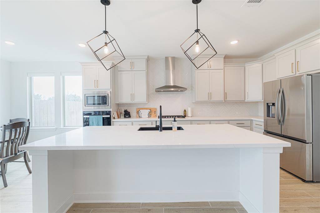 Island kitchen features quartz counters and custom lighting.