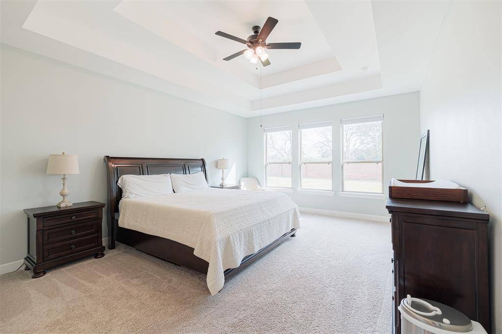 The primary suite offers tray ceilings and wall of windows overlooking the backyard.