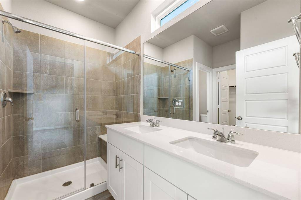 A spa-like primary bathroom featuring an expansive large walk-in shower, modern tile work, and dual sinks with sleek cabinetry.