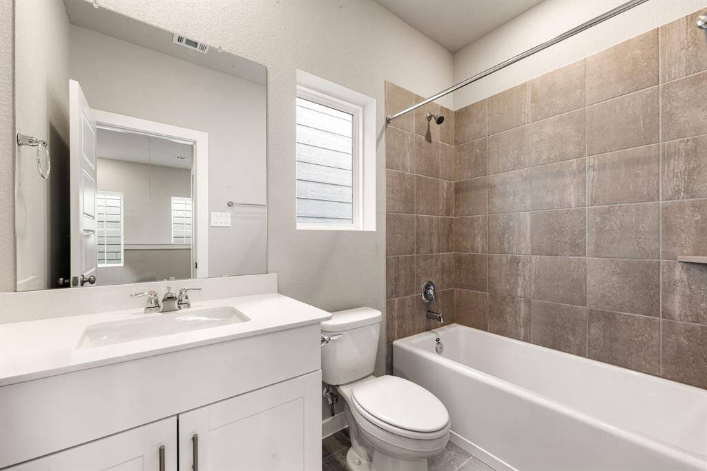 Secondary bathroom features light countertops and cabinets, custom paint, shower/tub combo with tile surround, large mirror, tile floors, sleek fixtures and modern finishes, plenty of space to accommodate any visiting family or guests.