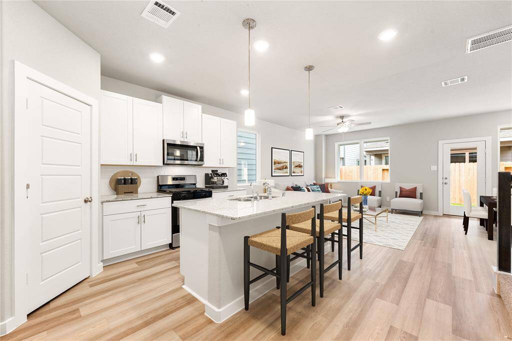 Bright and spacious open-concept kitchen and living area, featuring a large island with seating, sleek white cabinets, and an abundance of natural light—perfect for gatherings and everyday living. *Virtually Staged