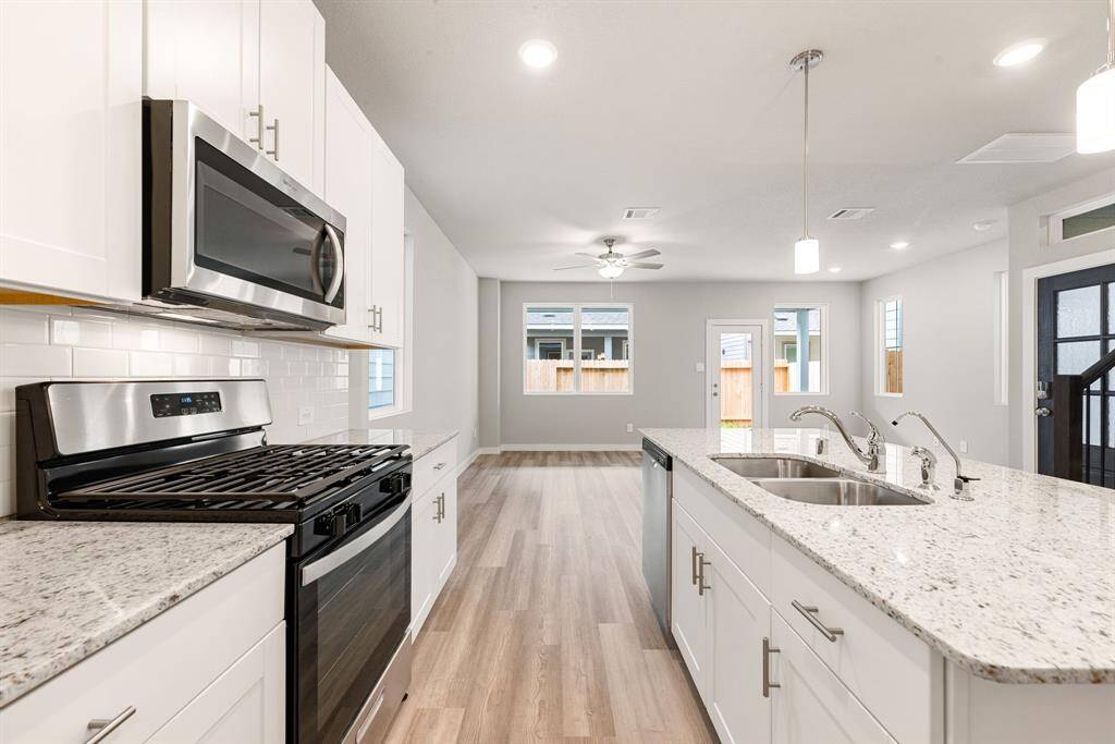 This stunning kitchen displays such a beautiful contrast with the dark stained cabinets, custom neutral paint, granite countertops, light modern backsplash, and SS appliances, oversized kitchen island with extra storage, breakfast bar, recessed lighting, high ceilings and walk in pantry.