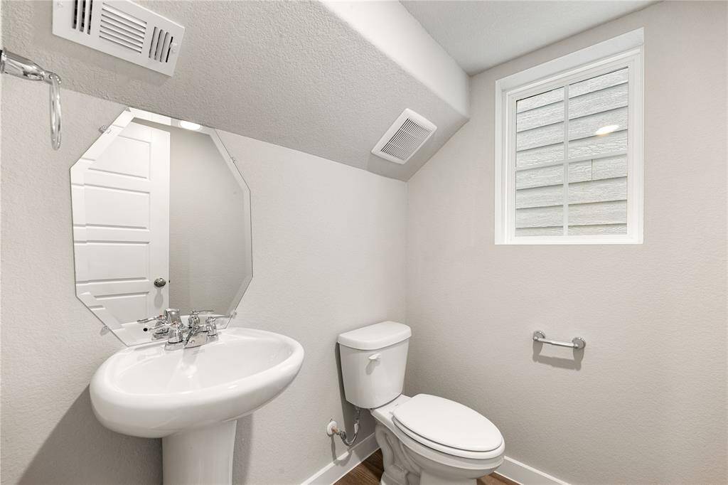 Convenient half bath off the main living area, featuring a pedestal sink and natural light—ideal for guests.