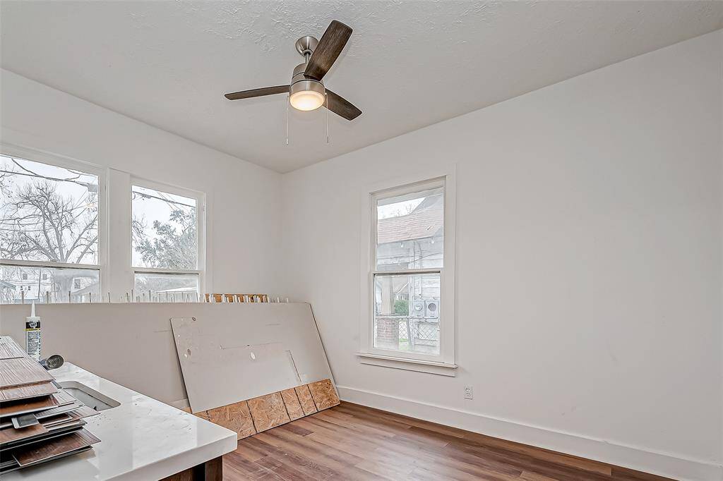 This bright and open space offers flexibility for a variety of uses. The built-in sink adds convenience, whether for a hobby area, a small kitchenette setup, or an additional workspace. The ceiling fan ensures comfort, while the neutral white walls and wood flooring keep the space fresh and adaptable to different needs.