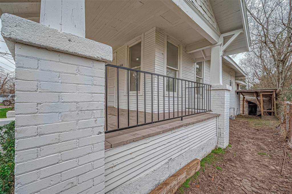The covered front porch extends across the home, with black railings adding contrast to the crisp white exterior.
