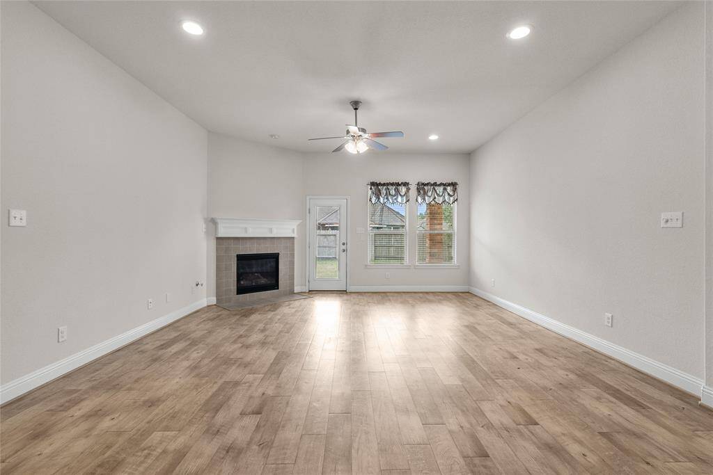 This spacious, well-lit living room featuring a contemporary design with a fireplace and recessed lighting. The room provides direct access to the backyard through a glass door.