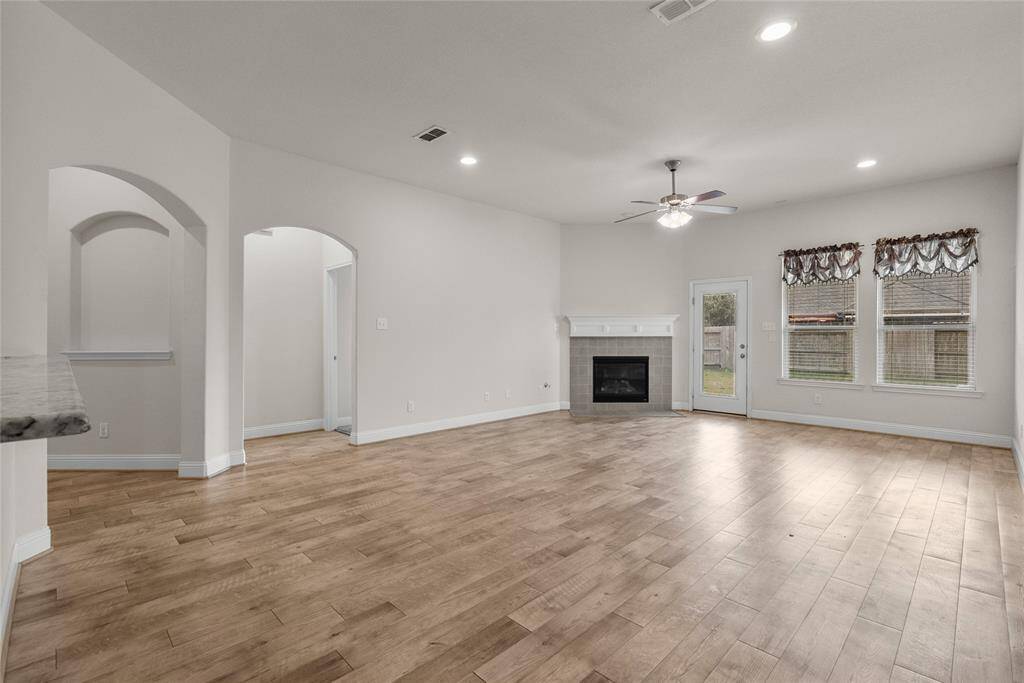 This is a spacious, well-lit living room featuring elegant archways leading to other parts of the home. There's also access to the backyard