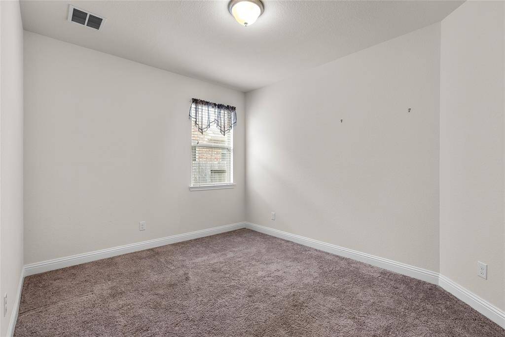 Secondary downstairs bedroom.  The space is well-lit with a central ceiling light.