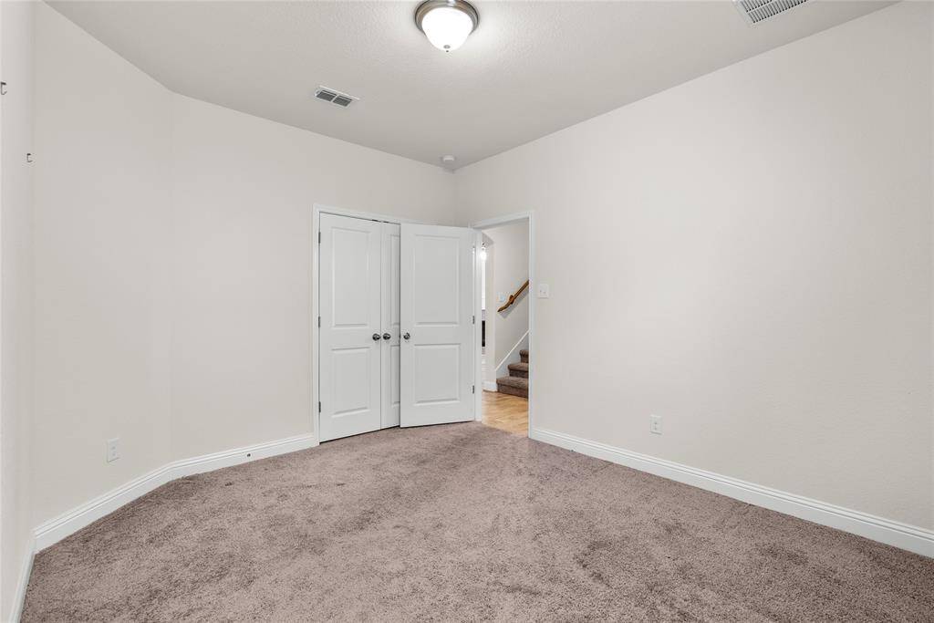 Second downstairs bedroom featuring a double-door closet and an open doorway leading to a staircase.